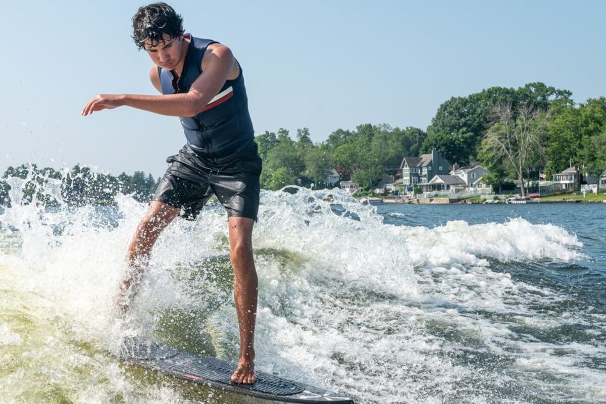 Wakesurfer riding the wave behind a deck boat