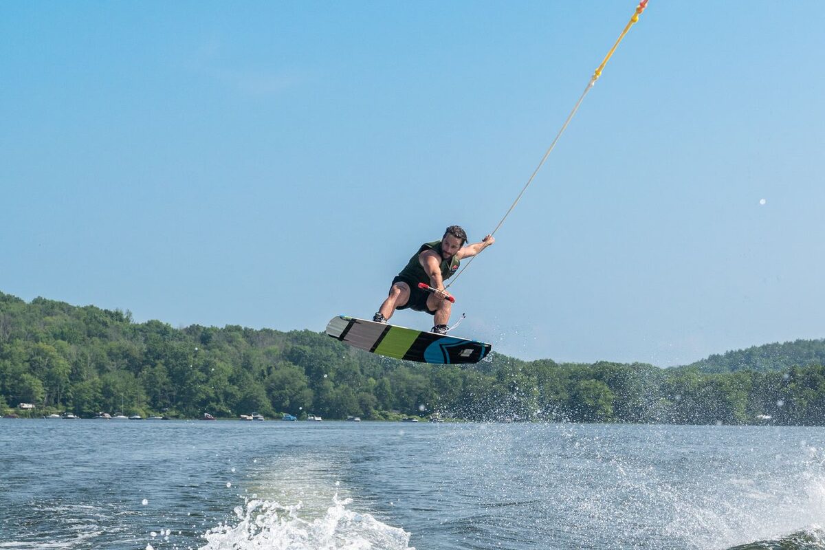 Wakeboarder catching air off the wake behind a ski boat
